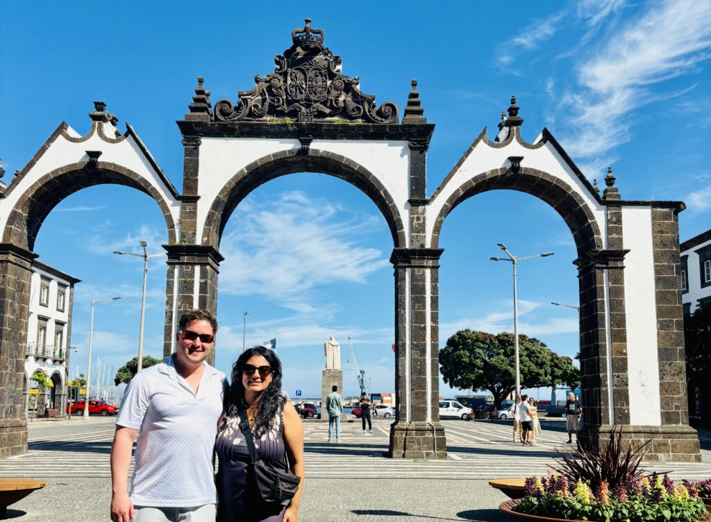 Couple standing in front of Portas da Cidade gates in Ponta Delgada